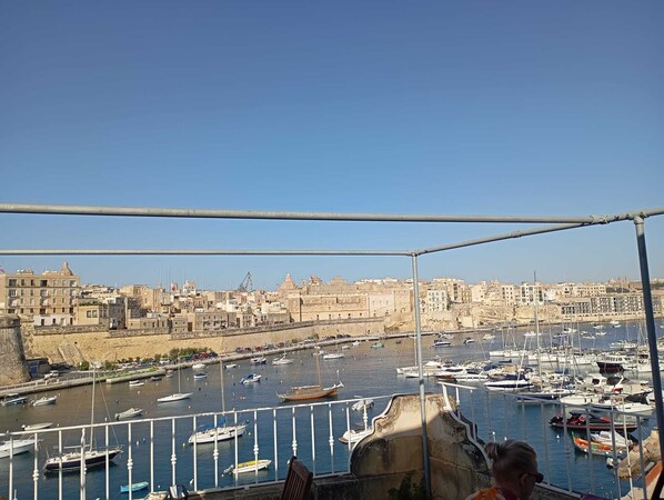 A harbor with numerous boats docked, a clear sky, and a cityscape in the background. - Villa Del Porto (Kalkara)