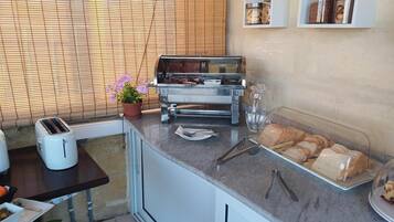 Una cocina con un tostador, una parrilla, un expositor de pan y una planta en maceta.