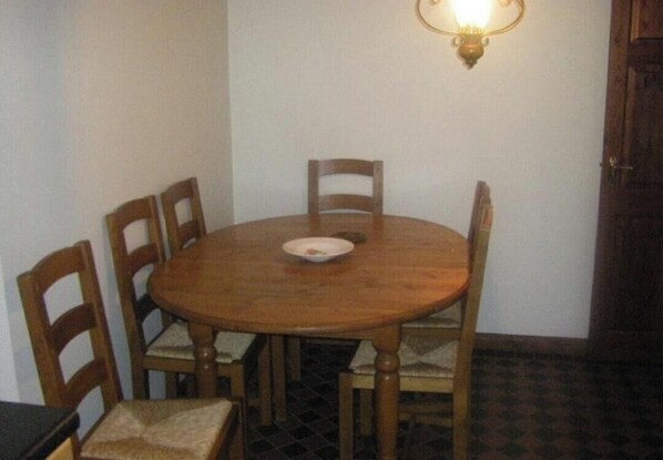 A round wooden dining table with four chairs, a single plate, and a wall-mounted light fixture. - Spacious 4 Bedroom House in Limerick (Limerick)