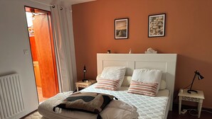 A neatly made bed with pillows and a blanket, a bedside table with a lamp, and two framed pictures on the wall.