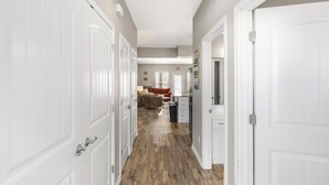 Un couloir avec des portes blanches, un coin cuisine et un salon avec un canapé et une table basse.