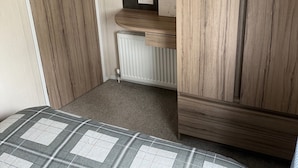 Ein gemütliches Schlafzimmer mit einem Holzschrank, einem Heizkörper und einem Bett mit Karo-Bettwäsche.
