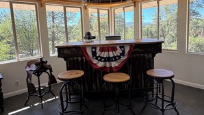 Zona de bar con decoración de bandera, ventanas amplias y una barra de madera rústica.