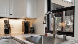 A kitchen with a stainless steel sink, a coffee maker, and a hand soap dispenser on the counter. - Bassett Creek Retreat (Golden Valley)