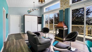 Una habitación acogedora con chimenea, un ventanal grande y un ventilador de techo.