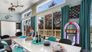 Un comedor amplio con una mesa larga, sillas color turquesa y un jukebox.