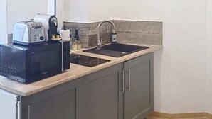 A modern kitchen with grey cabinets, a black countertop, a sink, and a toaster. - Port du Levant (Toulon)