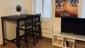 A compact living space with a dining area, a television, and a poster on the wall. - Port du Levant (Toulon)