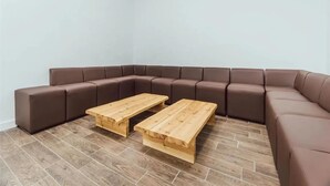 A corner living room with a brown sectional sofa and two wooden coffee tables. - Student Only Lomax Halls (Stoke-on-Trent)