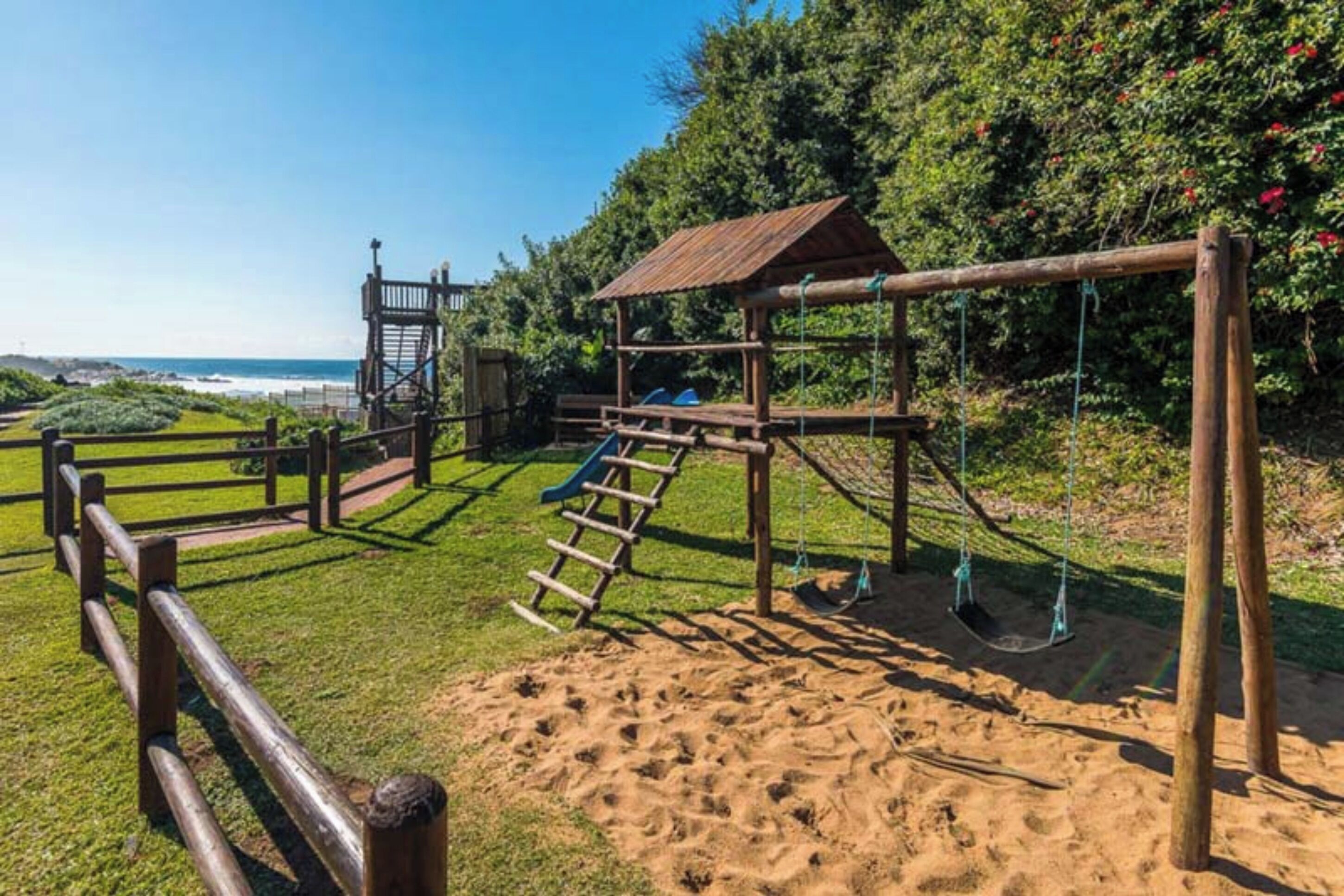 A playground with a wooden swing set, a slide, and a climbing structure.