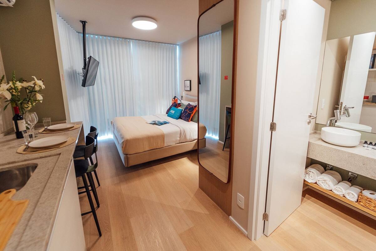 Une chambre d’hôtel moderne, équipée d’un lit, d’une table de chevet et d’un grand miroir.