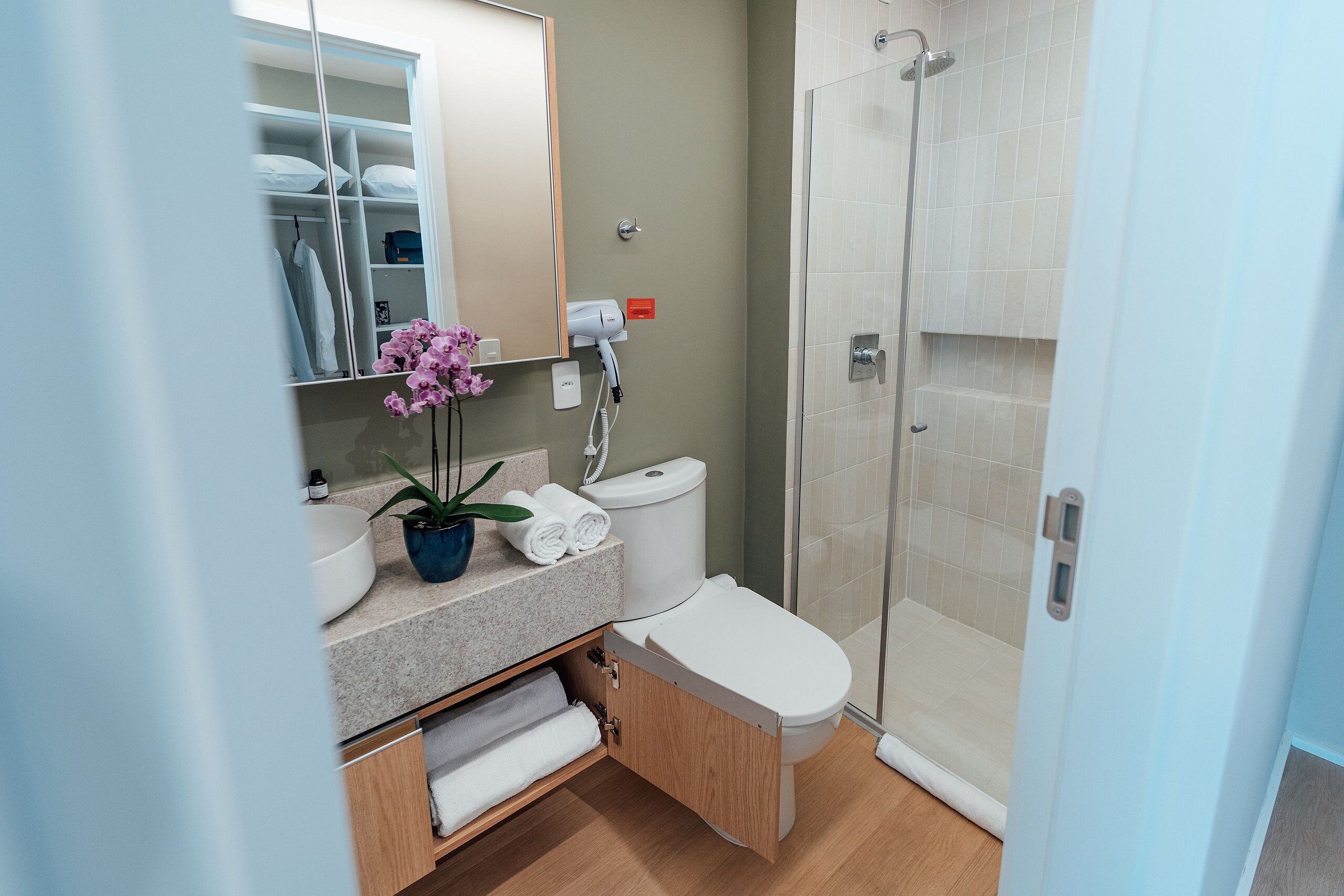 Ein modernes Badezimmer mit integriertem Waschbecken, Toilette und Duschkabine.