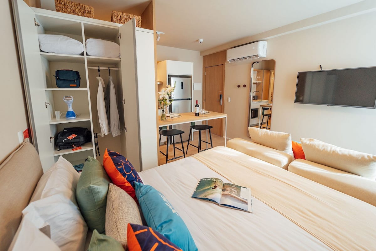 Une chambre d’hôtel équipée d’un lit, d’un bureau, d’une télévision, d’une armoire et d’une kitchenette.