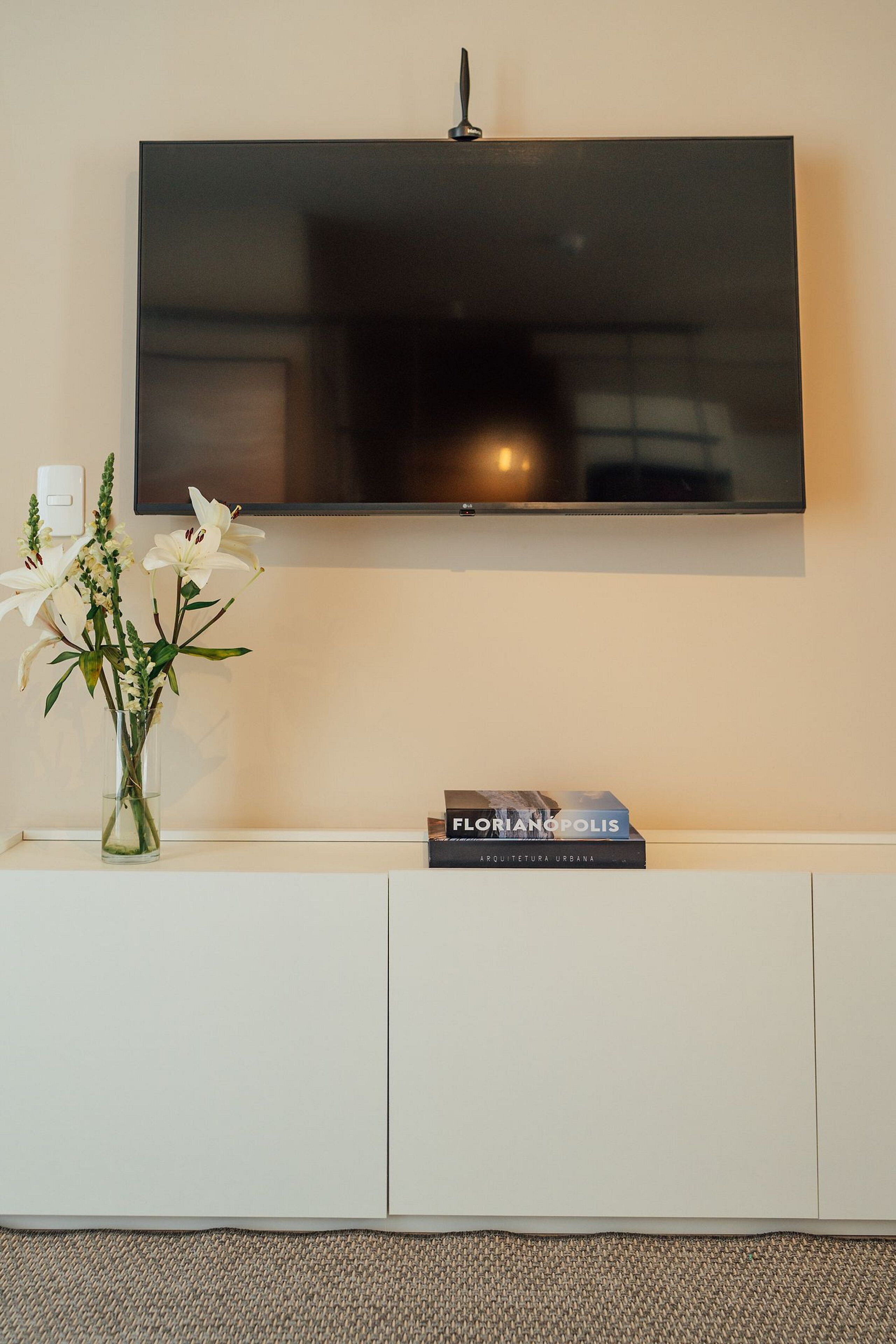 Un televisor de pantalla plana montado en la pared sobre un mueble blanco.