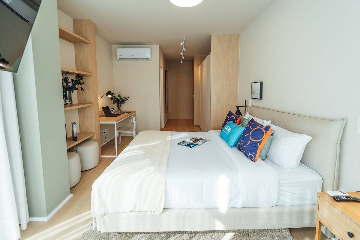 Une chambre moderne avec un grand lit, des tables de chevet, un bureau avec une chaise et une armoire.