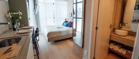 A modern bedroom with a bed, bedside table, and a large mirror.