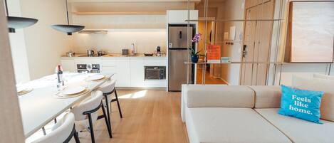 A modern kitchen with a dining area, a sofa with a pillow, and a sign on the wall.