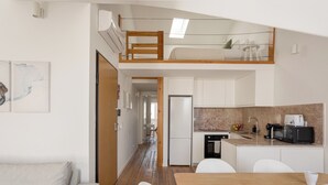 A modern apartment with a loft bedroom, a kitchenette, a dining area, and a living room. - Bridgeview Alcântara – The 3BR Loft Edition (Lisbon)