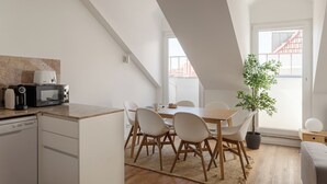 A modern kitchen with a dining area, a microwave, a coffee maker, and a potted plant. - Bridgeview Alcântara – The 3BR Loft Edition (Lisbon)