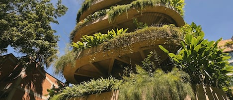 Un edificio de varios pisos con balcones cubiertos de follaje.