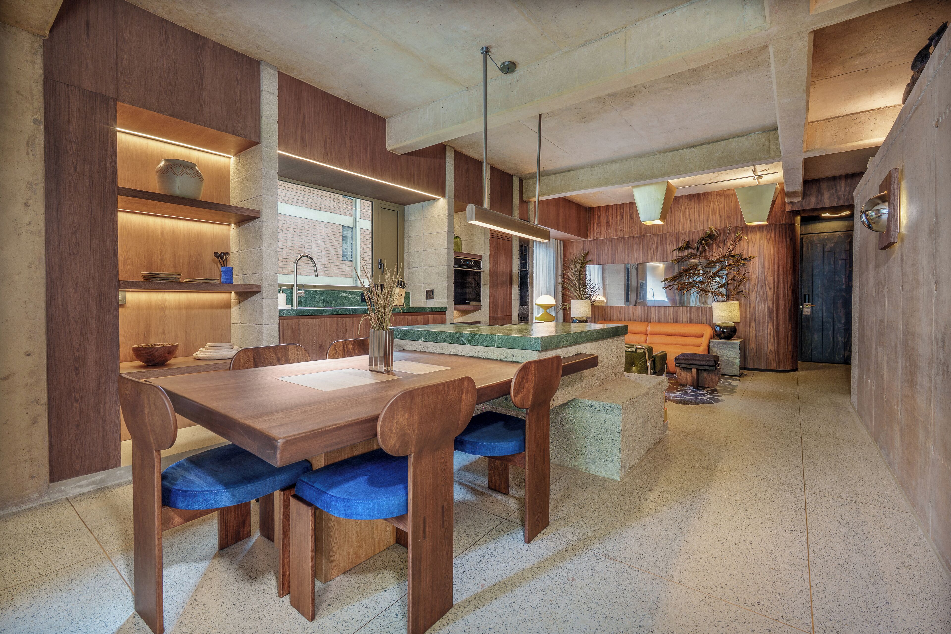 Eine moderne Küche mit Holzschränken, einer zentralen Kochinsel und blauen Sitzgelegenheiten.