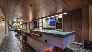 A modern kitchen with a stone countertop, wooden cabinets, and a view of the city at dusk. - 23 Living (Medellín)