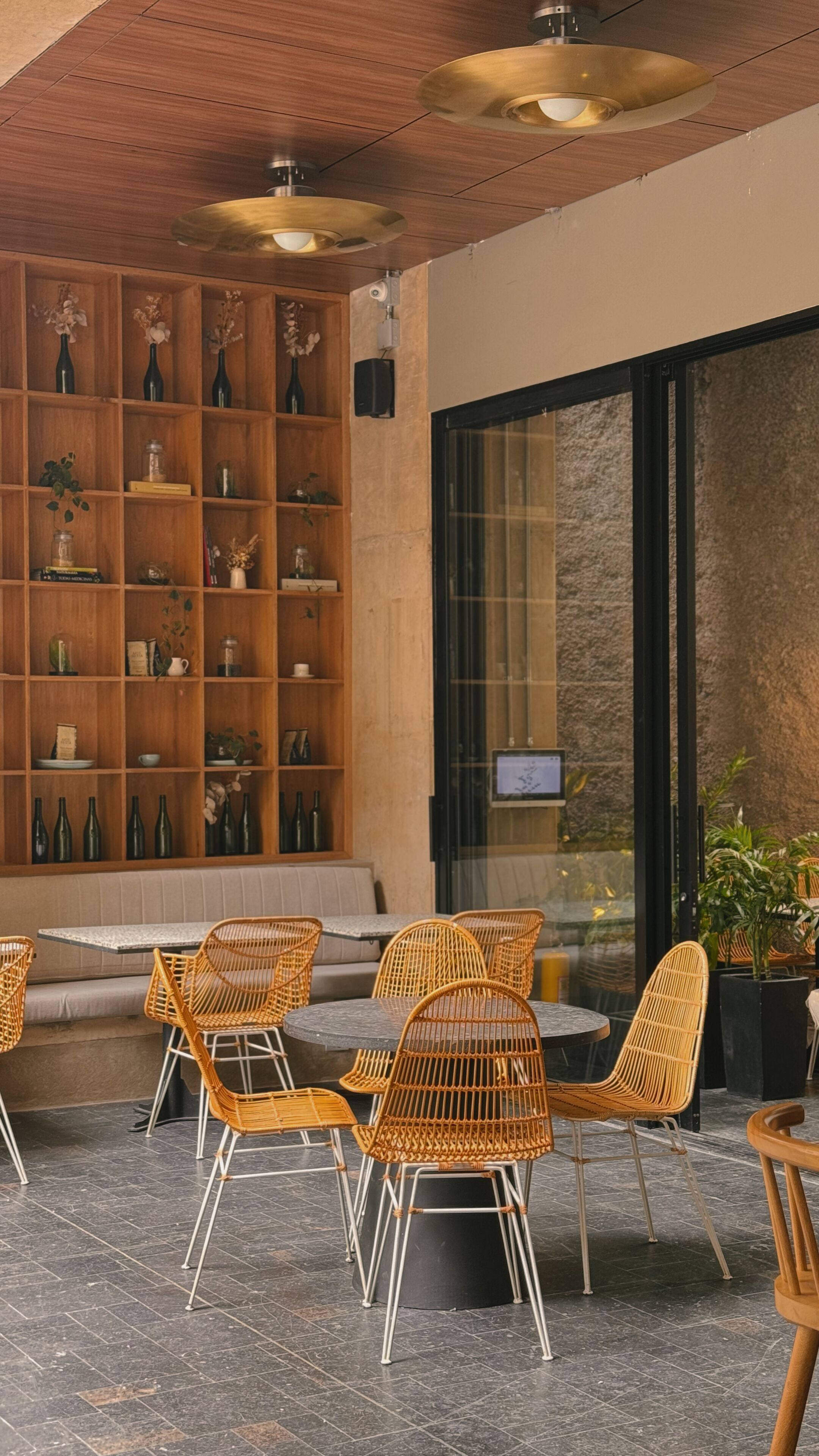 A modern interior with a wooden bookshelf, wicker chairs, and a stone wall.