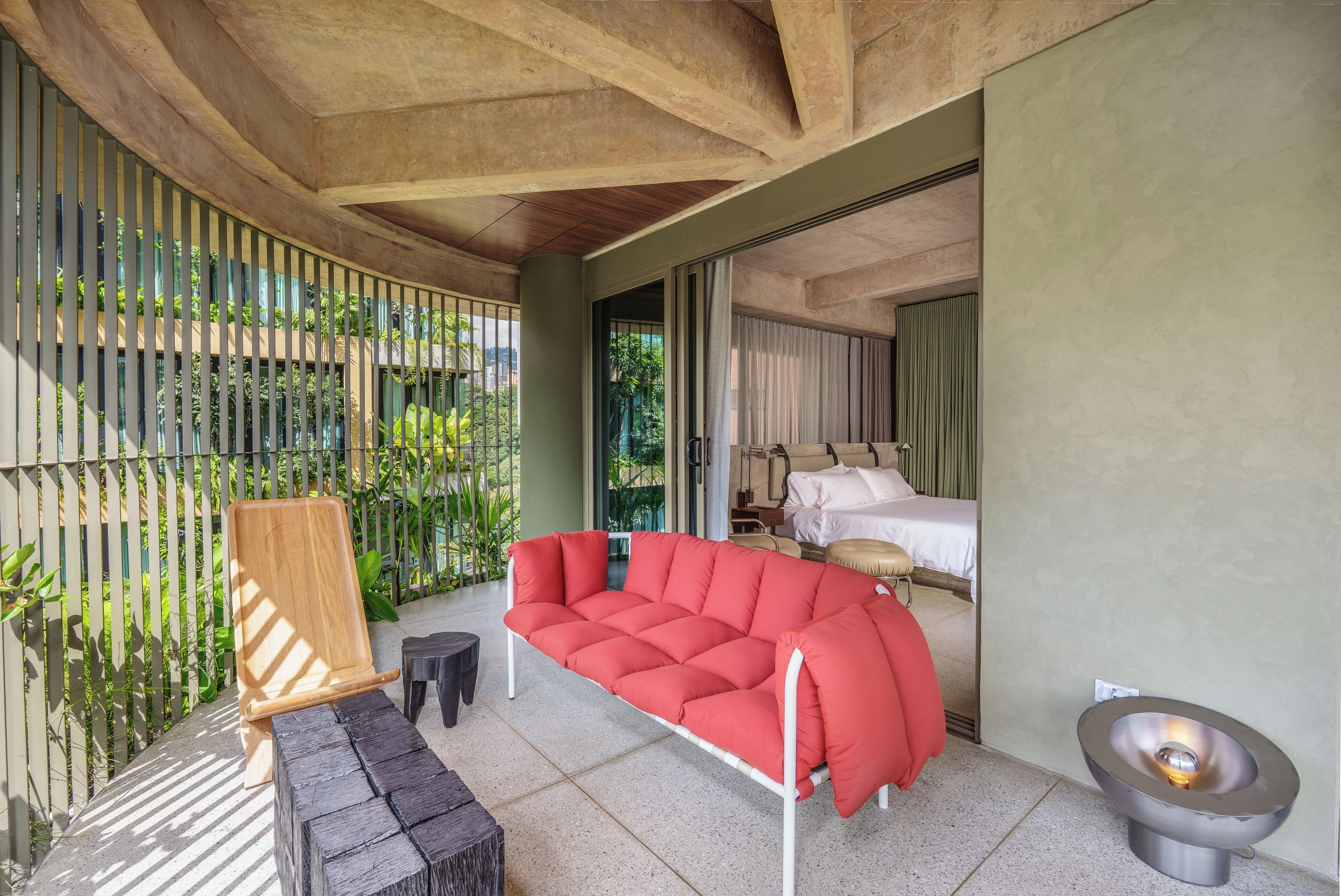 A modern room with a red sofa, a small wooden chair, a unique toilet design, and a bed with white linens.