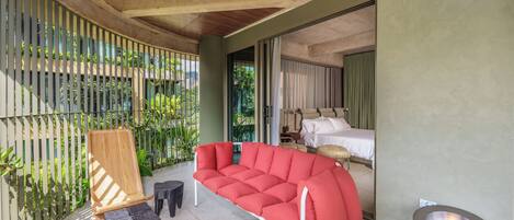 A modern room with a red sofa, a small wooden chair, a unique toilet design, and a bed with white linens.