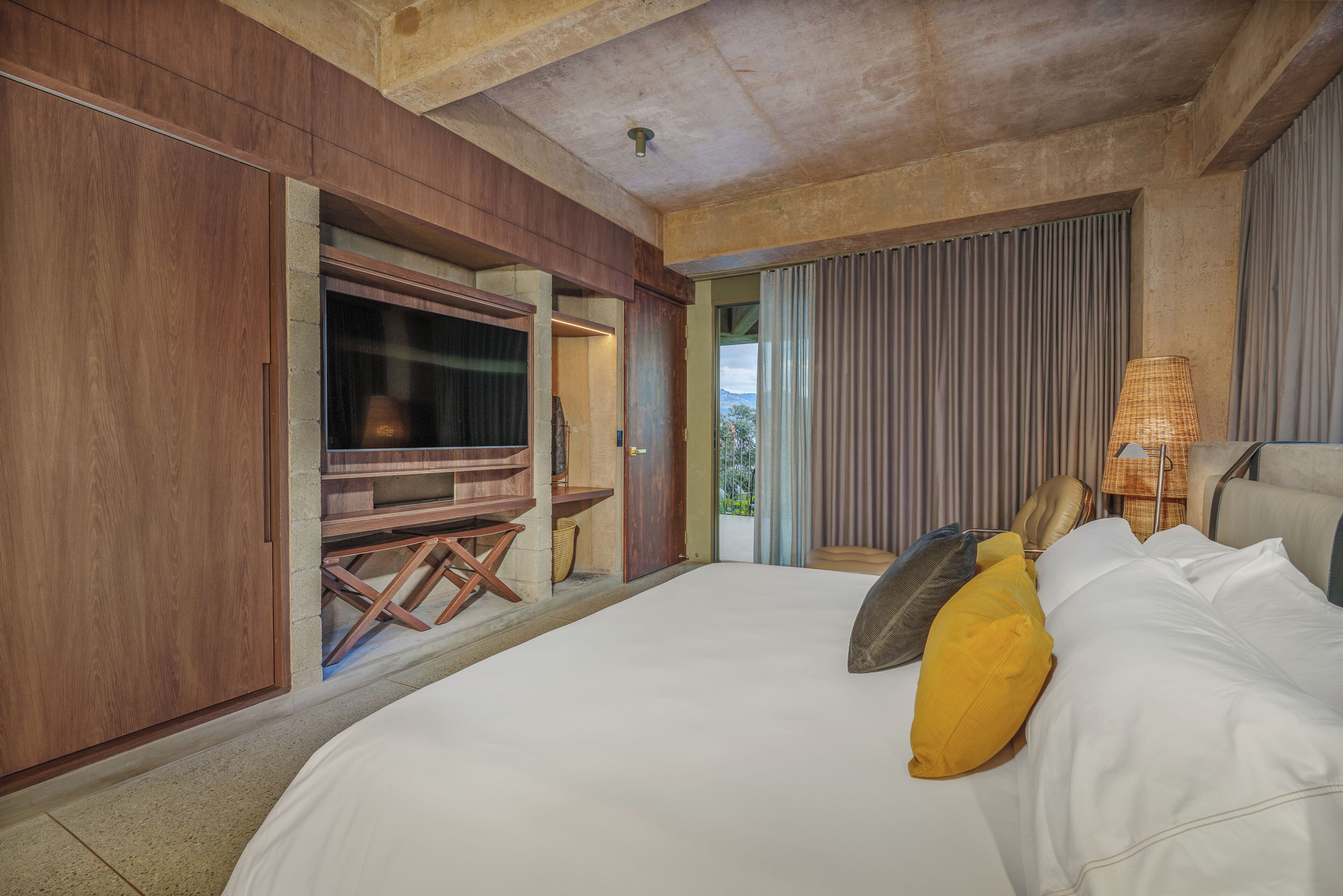 A bedroom with a large bed, a wooden desk, and a television.