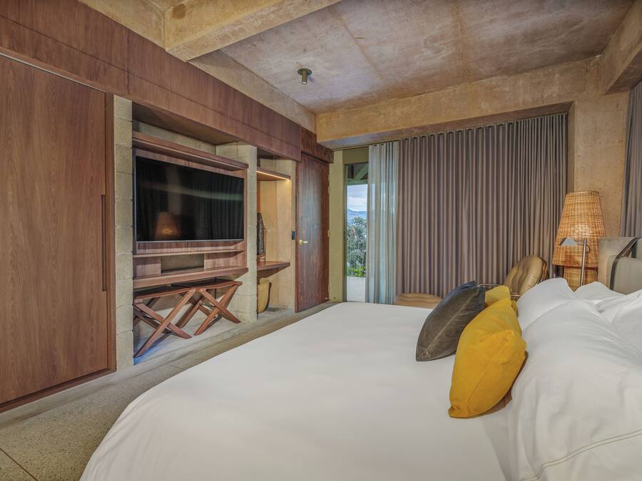 A bedroom with a large bed, a wooden desk, and a television.