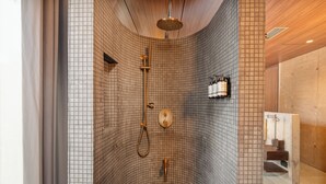 A modern shower with a curved ceiling, tiled walls, and a wooden panel design. - 23 Living (Medellín)