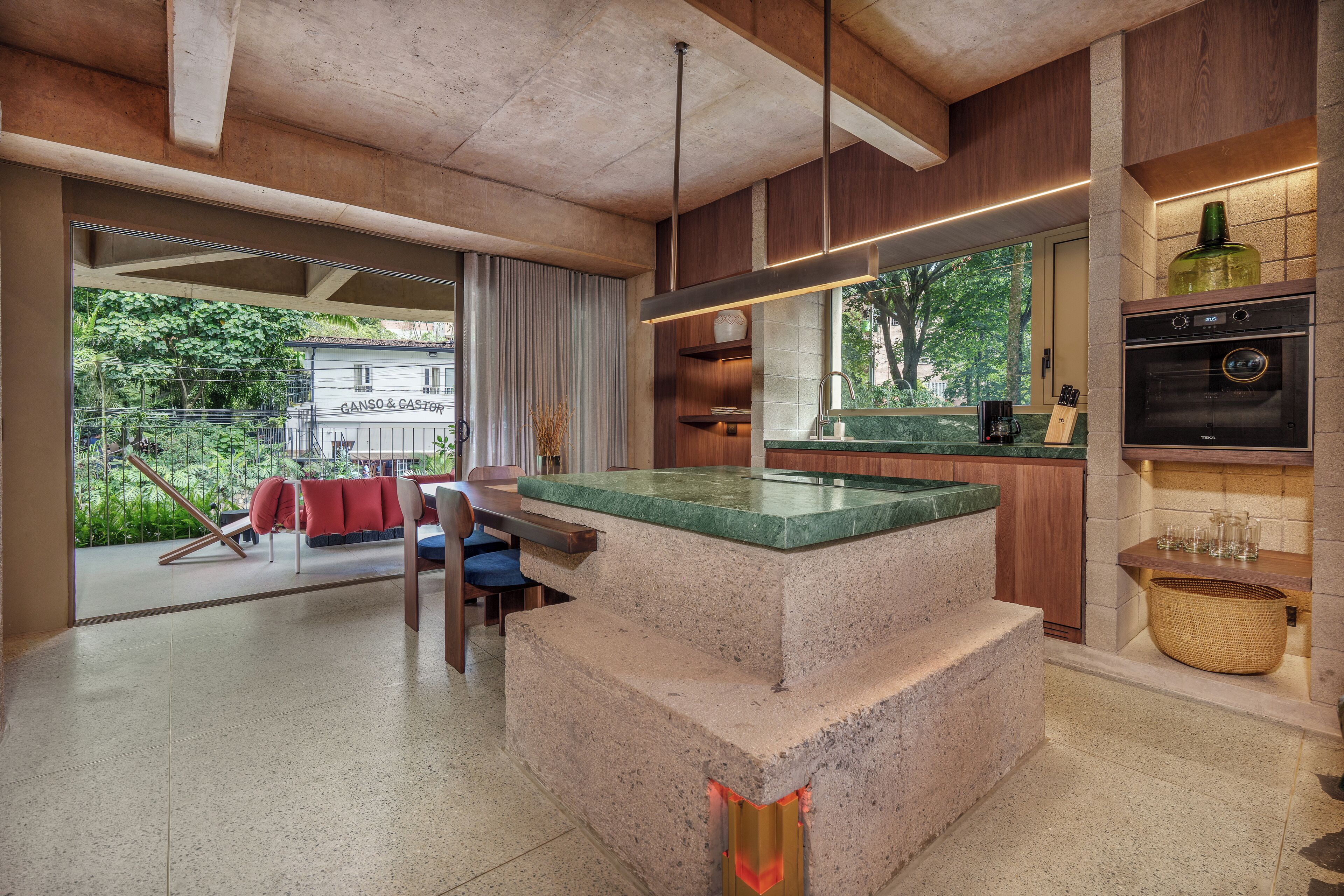 A modern kitchen with a central island, built-in oven, and a large window offering a view of the outdoors.