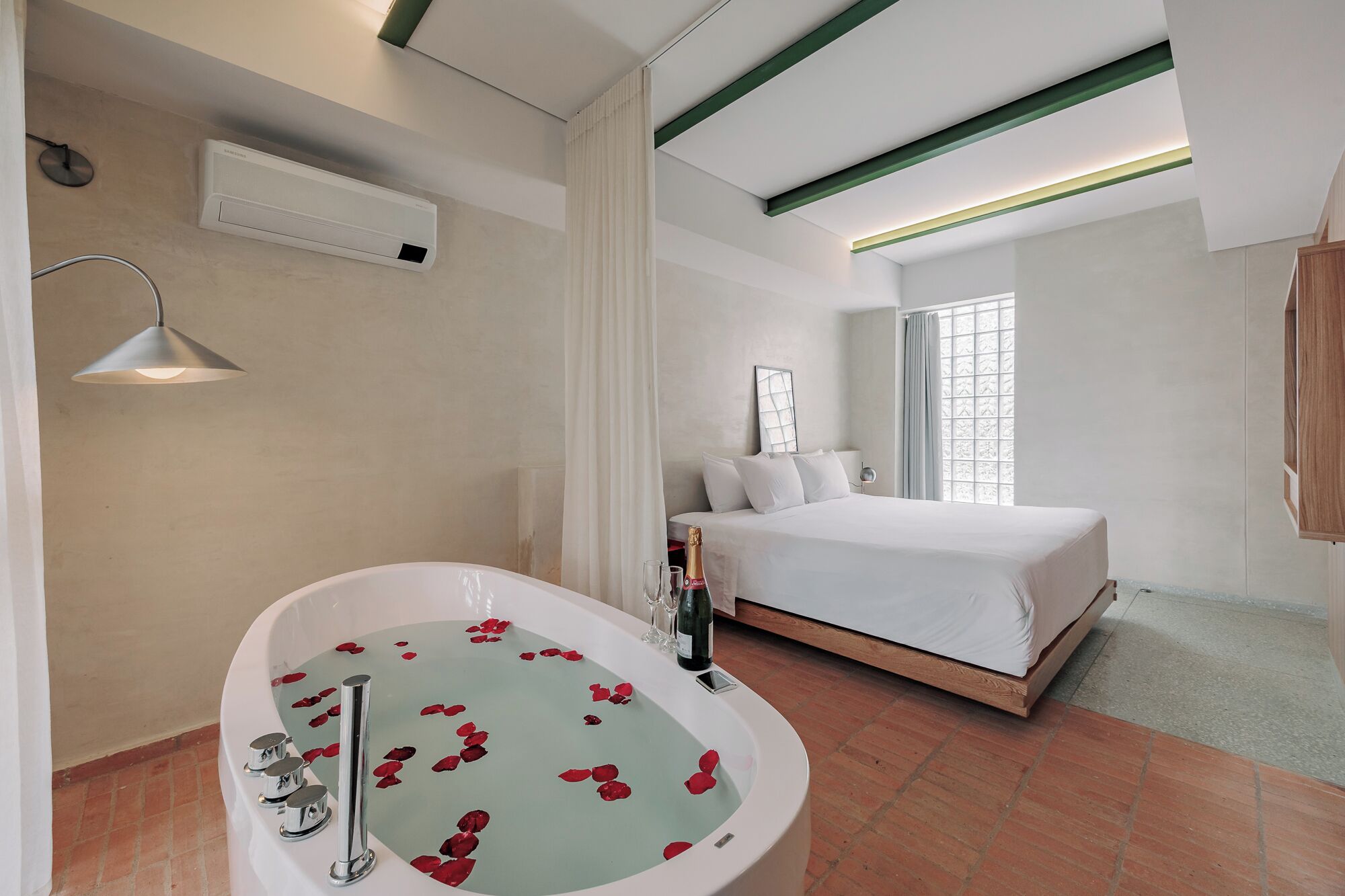Een hotelkamer met een groot bad, een bed, een raam met uitzicht en een plafond met groene balken.