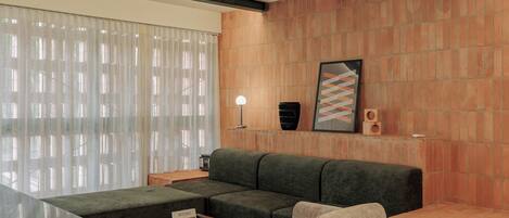 A modern living room with a sectional sofa, a small table, and a wall-mounted speaker.