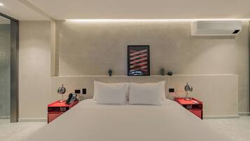 Una habitación de hotel moderna con una cama grande, dos mesitas de noche con lámparas, aire acondicionado instalado y una obra de arte enmarcada en la pared.