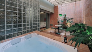 Un espace bien-être comprenant un jacuzzi, une table avec des chaises et des plantes en pot.