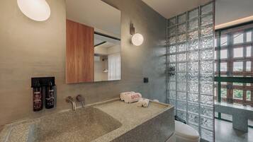 A bathroom with a granite sink, a wooden cabinet, a mirror, and a glass partition with a view.