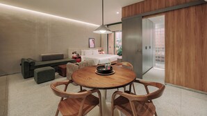 Une chambre d’hôtel moderne dotée d’un coin repas, d’un canapé, d’un lit et offrant une vue sur l’extérieur.