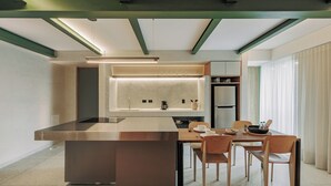 Une cuisine moderne dotée d’un îlot central, d’une table à manger, de chaises et d’un réfrigérateur.