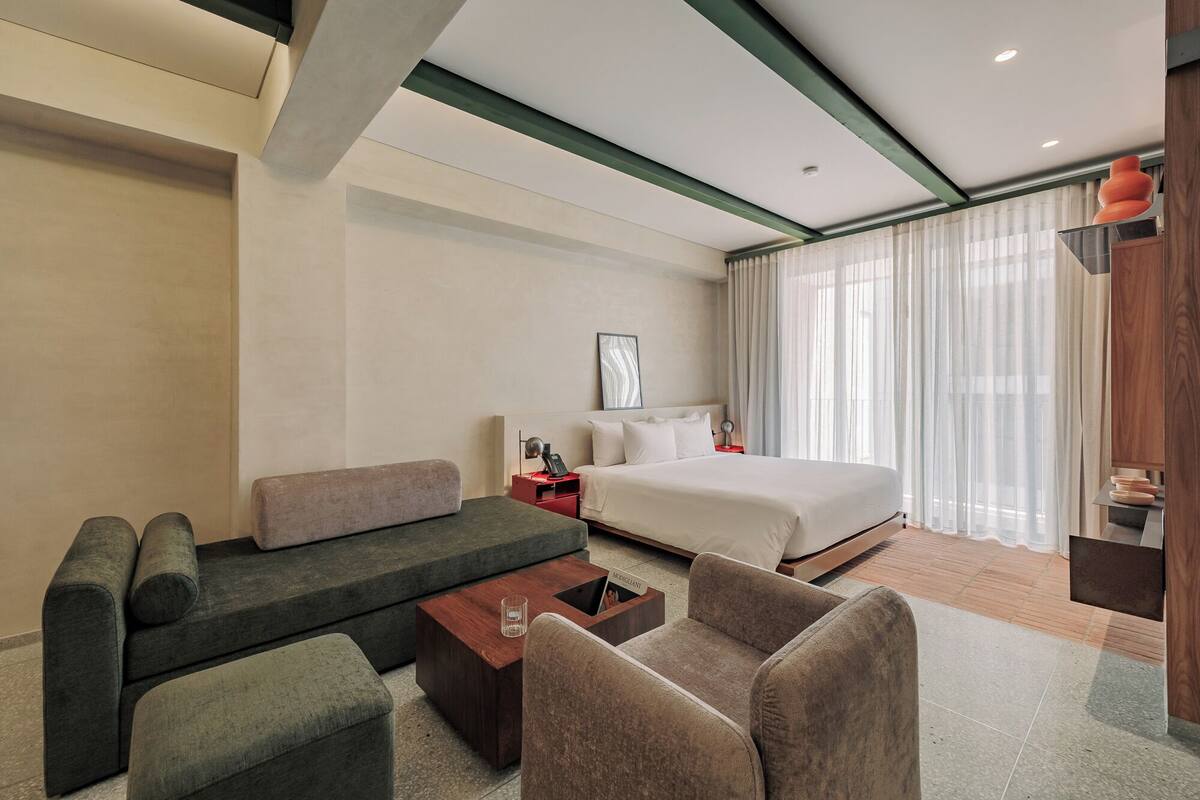 Una habitación de hotel moderna con sofá, cama, mesita de centro y escritorio.
