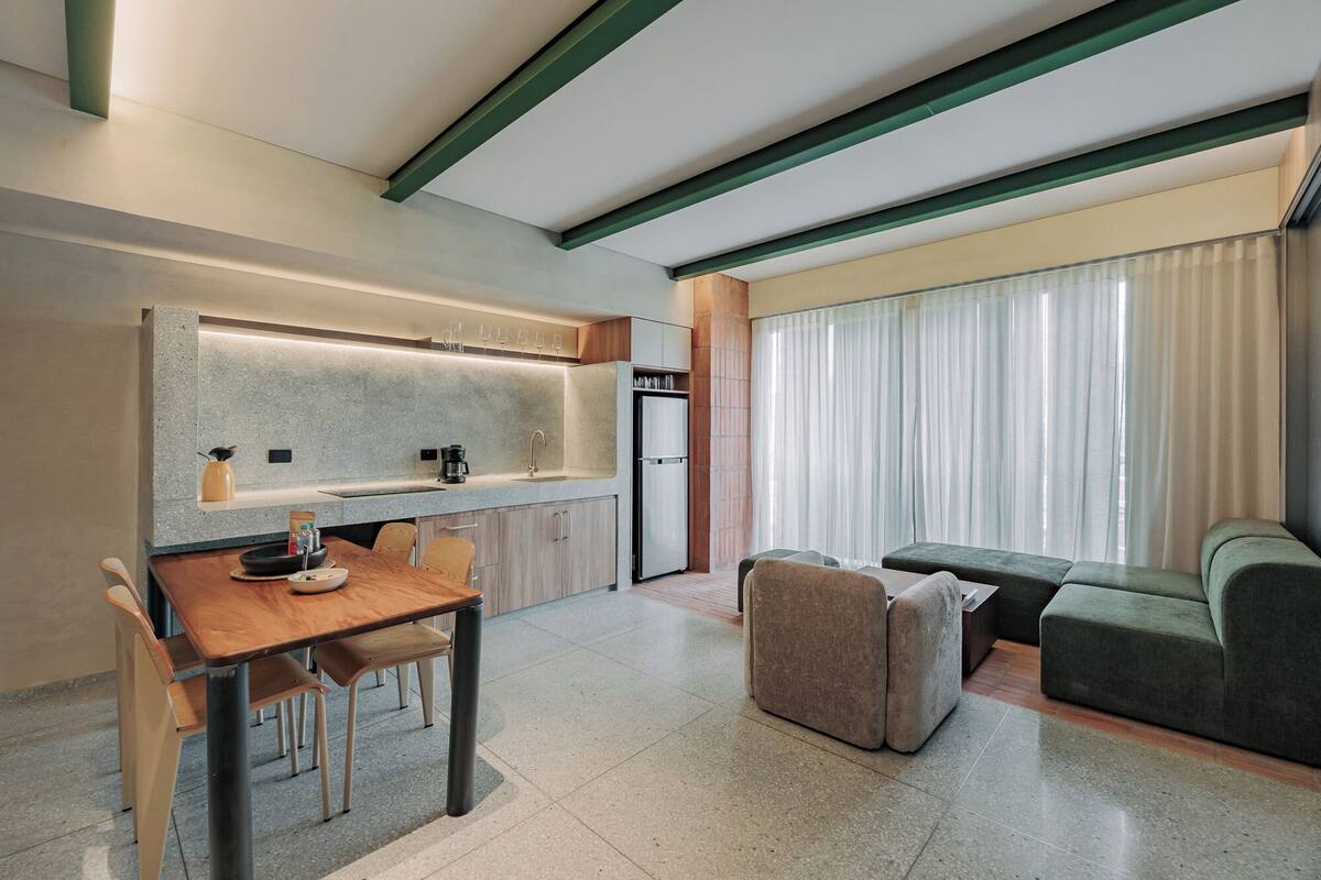 Una cocina moderna con comedor, un sofá y un ventanal con cortinas.