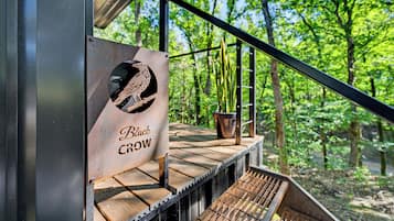 Une terrasse en bois avec une rambarde en métal, une enseigne indiquant « Black Crow », et un pot de fleurs.