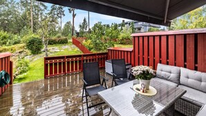 A covered outdoor area with a wooden deck, a red fence, and a seating area with a table and chairs. - Kazan Hotel Norge (Skien)