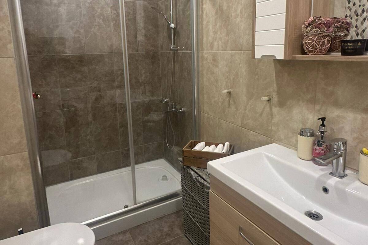 A bathroom with a glass-enclosed shower, a white toilet, a wooden vanity with a sink, and a mirror above the vanity.