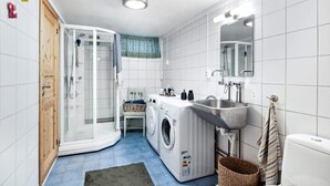 A compact, modern bathroom with a built-in washing machine, a shower enclosure, and a sink. - Kazan Hotel Norge (Skien)