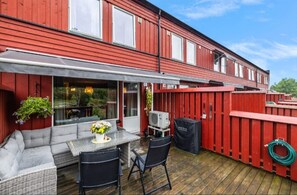 A red wooden deck with a covered outdoor seating area, a grill, and a hose. - Kazan Hotel Norge (Skien)