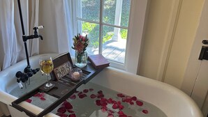 Una bañera llena de pétalos de rosa, una copa de vino y un letrero que dice 'Baño 5'.