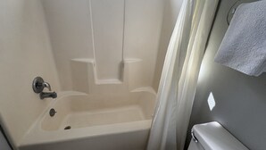 A bathroom with a bathtub, a shower curtain, and a towel rack. - WESTERN STATESINN (San Miguel)