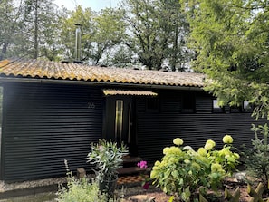 Set amidst lush gardens, this charming building offers a serene entrance with a door and small porch.